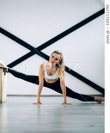 Joyful confident adult athlete stretching legs in sport club 108211398