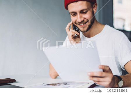 Content hipster male with paper talking on phone 108211861