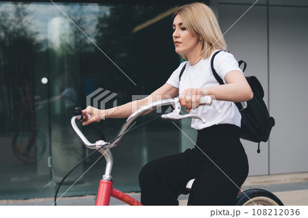 Modern casual female riding vintage bicycle on street 108212036