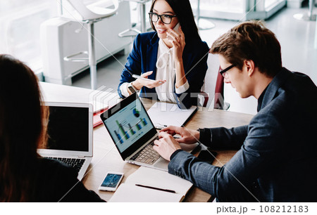 male typing on netbook while female colleague having mobile phone conversation male typing on netbook while female colleague having mobile phone conversation 108212183