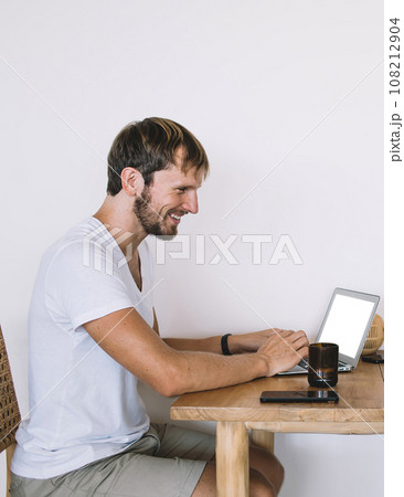 Cheerful young beautiful couple having meal eating while browsing laptop sitting at table 108212904
