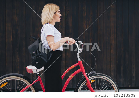 Adult female cyclist walking with bicycle on street 108213508