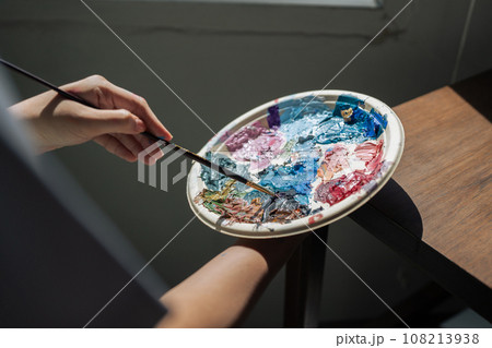 artist brush mix color painting on palette is holding in his hand closeup artist brush mix color painting on palette is holding in his hand closeup 108213938