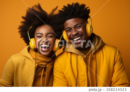 joyful couple of teenagers dancing, enjoying cool music in stereo headphones, listening to a pleasant popular track, actively moving on a yellow background, wearing yellow clothes and with yellow 108214323