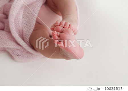 Close-up of tiny, cute, bare toes, heels and feet of a newborn girl, boy. Baby foot on pink soft coverlet, blanket. Detail of a newborn baby legs. Macro horizontal professional studio photo.  108216174