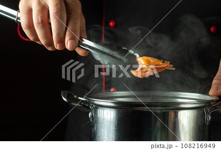 The chef prepares delicious shrimp in a pan in the kitchen. Delicious shrimp or prawn lunch concept for restaurant. The chef prepares delicious shrimp in a pan in the kitchen. Delicious shrimp or prawn lunch concept for restaurant. 108216949