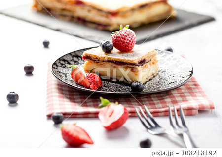 A piece of Napoleon cake with poppy seeds and cherries 108218192