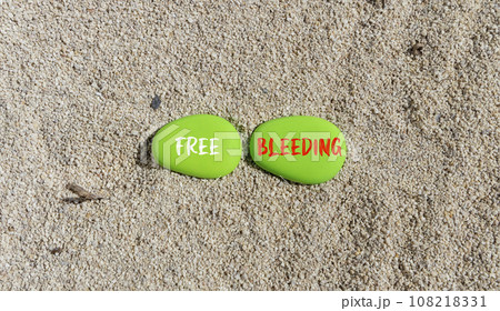 Free bleeding symbol. Concept words Free bleeding on beautiful green stone. Beautiful sea sand beach background. Gen Z, motivational, freedom free bleeding concept. Copy space. 108218331