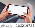 Hand holding black smartphone with blank screen for graphic display montage in the living room 108219785