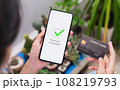 Hands holding smartphone with credit card and showing payment completed message on mobile. 108219793