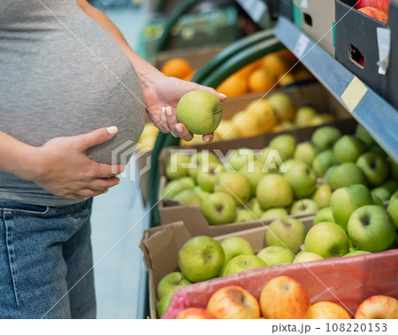 Pregnant woman chooses apples in the store. Pregnant woman chooses apples in the store. 108220153