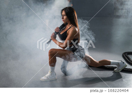Caucasian woman holds the ropes and does a lunge in the exercise machine. 108220404