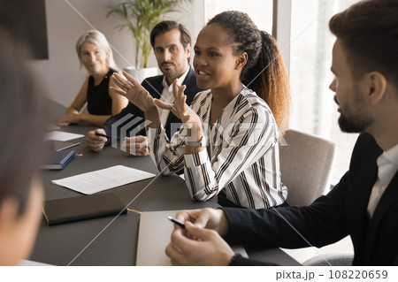 Positive engaged young African manager woman talking to colleagues Positive engaged young African manager woman talking to colleagues 108220659