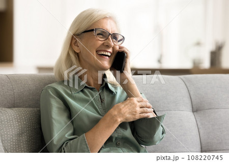 Cheerful pretty retired elderly woman in glasses speaking on cell Cheerful pretty retired elderly woman in glasses speaking on cell 108220745