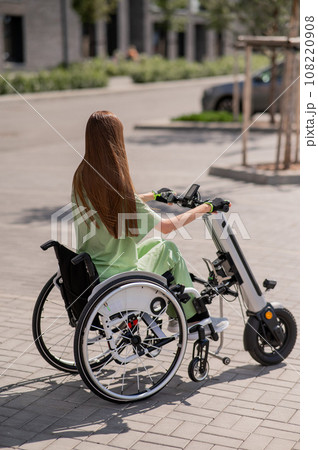 A woman in a wheelchair with an assistive device for manual control. Electric handbike.  108220908