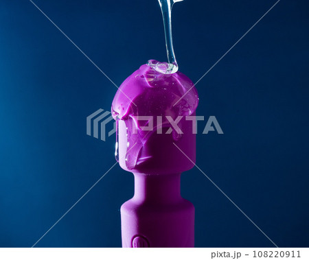 Intimate lubricant pours on a purple vibrator on a blue background. Intimate lubricant pours on a purple vibrator on a blue background. 108220911