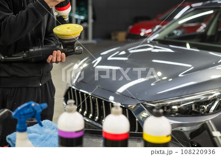 The master applies a special composition to the device for polishing the surface of the car body. The master applies a special composition to the device for polishing the surface of the car body. 108220936