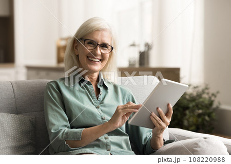 Happy pretty senior woman in glasses holding tablet Happy pretty senior woman in glasses holding tablet 108220988