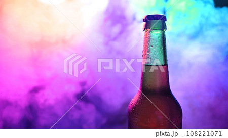 Beer bottle spinning in blue pink smoke. 108221071