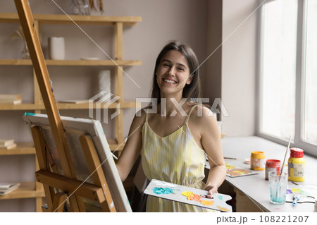 Painter woman posing with palette and paintbrush near easel Painter woman posing with palette and paintbrush near easel 108221207