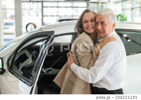 Mature Caucasian couple hugging. Elderly man and woman buying a new car. Mature Caucasian couple hugging. Elderly man and woman buying a new car. 108221285