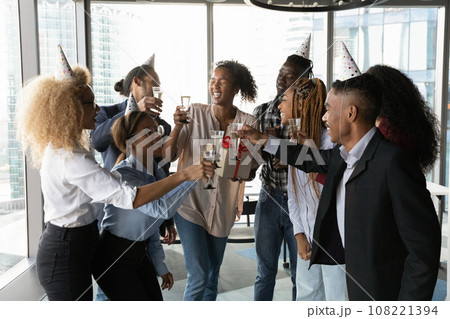 Excited employees celebrating African American businesswoman colleague birthday in office 108221394