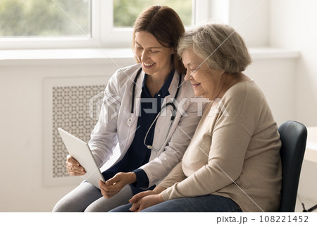Therapist show health test results on tablet to elderly patient 108221452