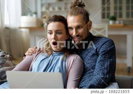 Shocked happy couple getting email message with surprising good news Shocked happy couple getting email message with surprising good news 108221655