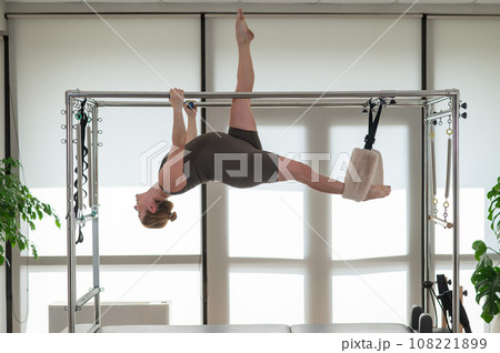 A pregnant woman is doing Pilates on a reformer. Aerial gymnastics.  108221899