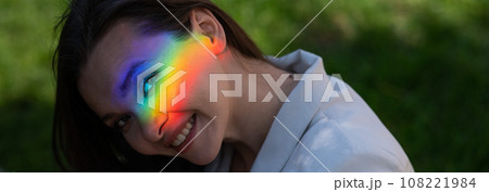Portrait of caucasian woman with rainbow beam on her face outdoors. 108221984