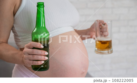 Pregnant woman holding glass and bottle of beer. Pregnant woman holding glass and bottle of beer. 108222005