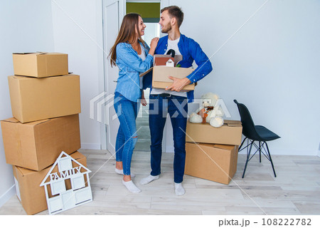 Young happy family with cardboard boxes opening door of their new home and coming in at empty flat. 108222782