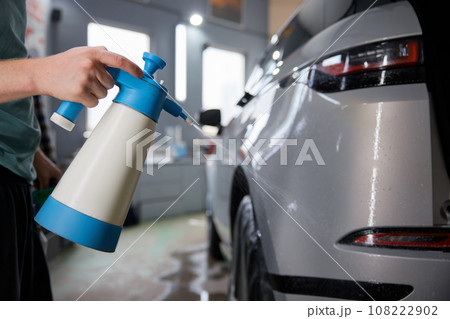 Car service man spraying water on car body before applying anti-gravity film 108222902