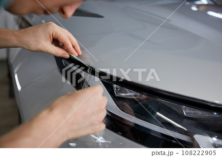 Worker detailer cutting off excess of polymer protective outer coating closeup 108222905