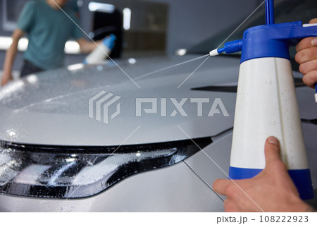 Closeup professional detailer hand applying auto body coating at car service Closeup professional detailer hand applying auto body coating at car service 108222923