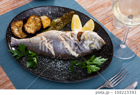 Dorada fish baked with lemon served with vegetable garnish 108223391