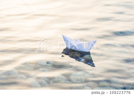 Origami white paper boat on blue deep water. Origami white paper boat on blue deep water. 108223776