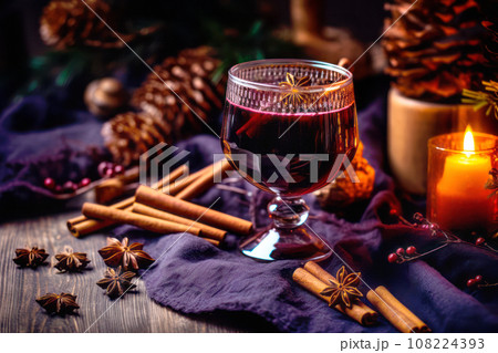 Christmas red mulled wine in a cup with cinnamon sticks, orange slices and winter decorations on wooden background 108224393