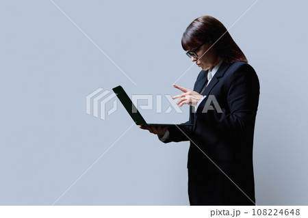 Serious mature business woman using laptop, on grey background 108224648