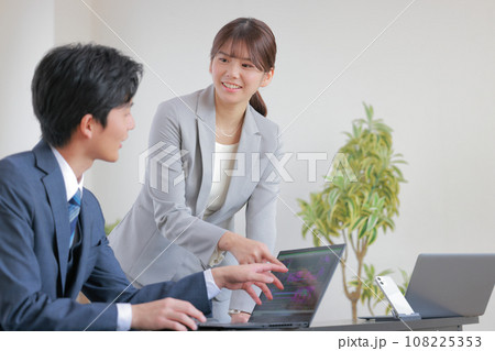 PCを見ながら意見交換するスーツの男女1 PCを見ながら意見交換するスーツの男女1 108225353