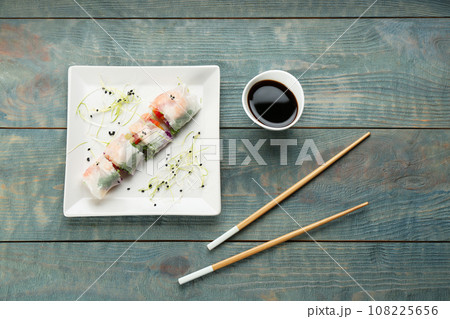 Delicious rolls wrapped in rice paper on light blue wooden table, flat lay 108225656