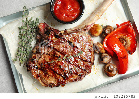 Delicious grilled ribeye with garnish on light table, top view 108225783