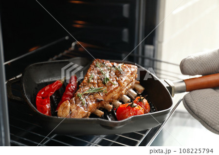 Chef taking delicious roasted ribs out of oven, closeup 108225794