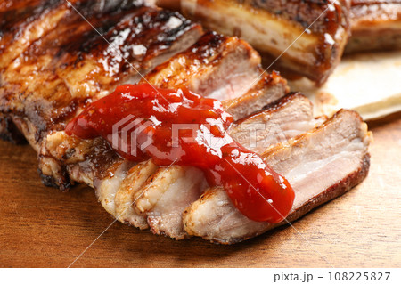Delicious grilled ribs with sauce on wooden table, closeup 108225827