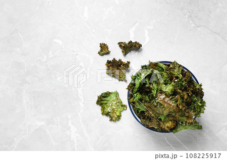 Tasty baked kale chips on grey marble table, flat lay. Space for text Tasty baked kale chips on grey marble table, flat lay. Space for text 108225917