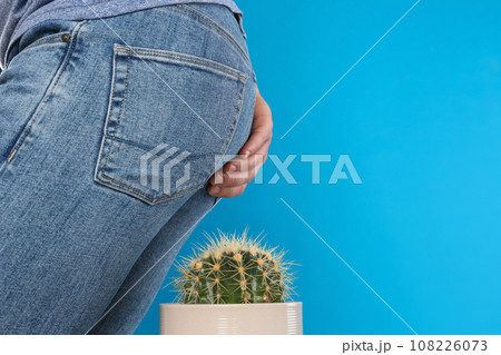 Man sitting down on cactus against light blue background, space for text. Hemorrhoid concept 108226073