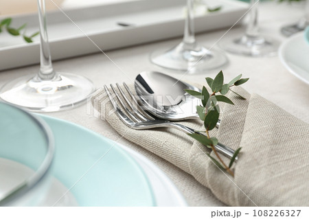 Elegant cutlery with green leaves on table, closeup. Festive setting Elegant cutlery with green leaves on table, closeup. Festive setting 108226327