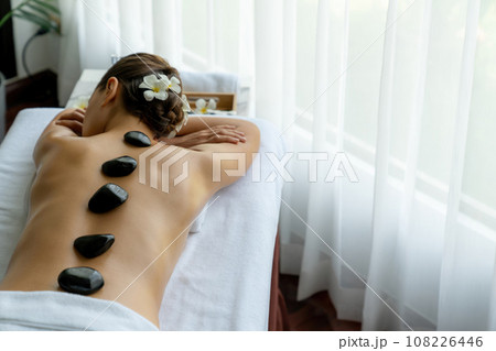 Hot stone massage at spa salon in luxury resort. Quiescent Hot stone massage at spa salon in luxury resort. Quiescent 108226446