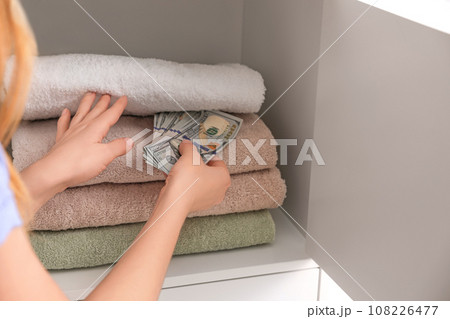 Woman hiding money between towels, closeup. Financial savings Woman hiding money between towels, closeup. Financial savings 108226477