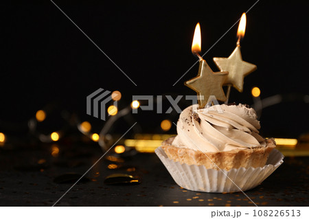 Birthday cupcake with candles on table against black background, space for text Birthday cupcake with candles on table against black background, space for text 108226513